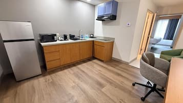 A compact kitchen with a refrigerator, microwave, sink, and wooden cabinets.