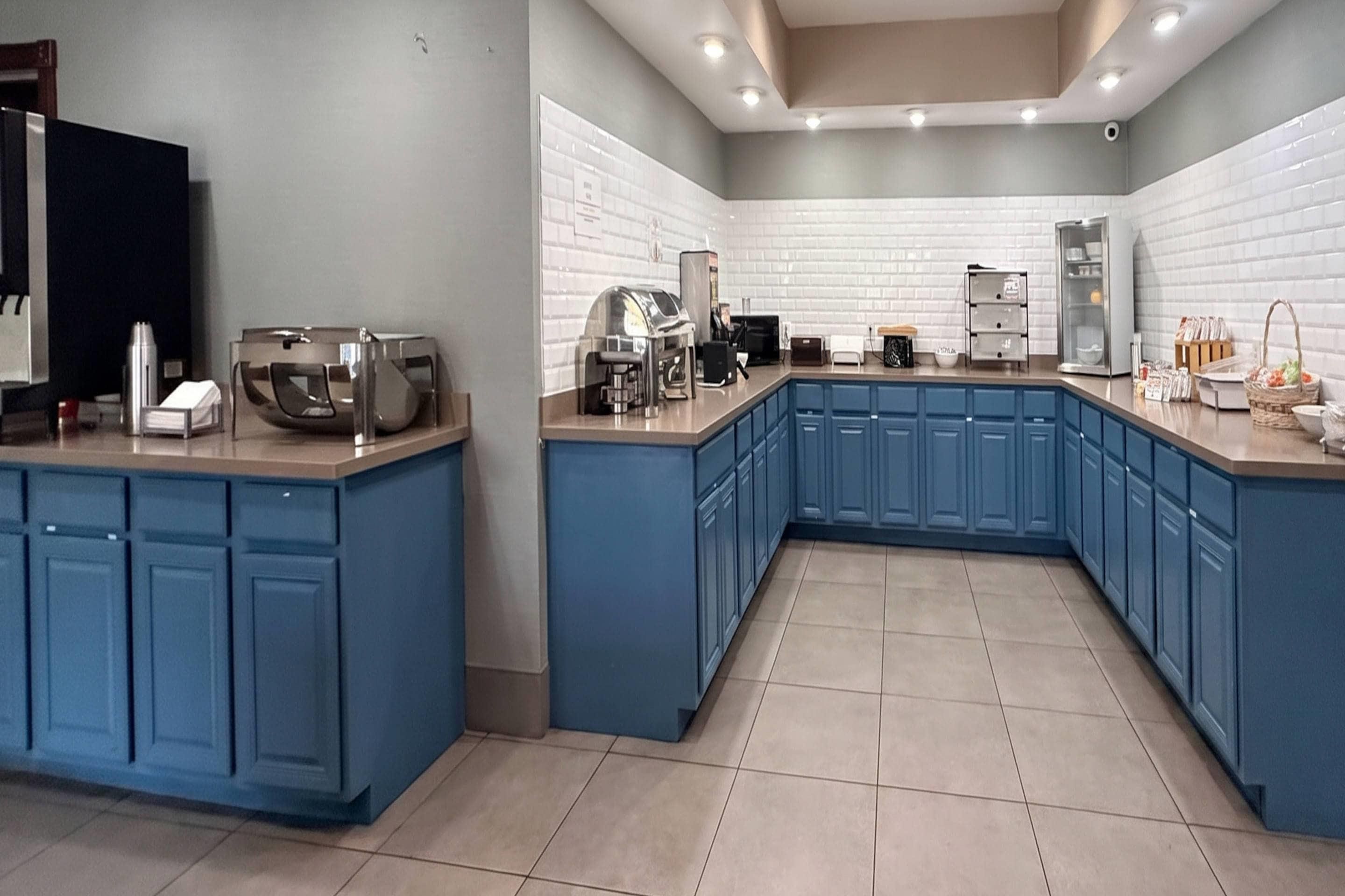 Una cocina moderna con armarios azules, horno empotrado y espacio para café.