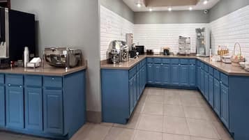 Una cocina moderna con armarios azules, horno empotrado y espacio para café.
