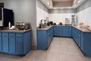 A modern kitchen with blue cabinets, a built-in oven, and a coffee station.