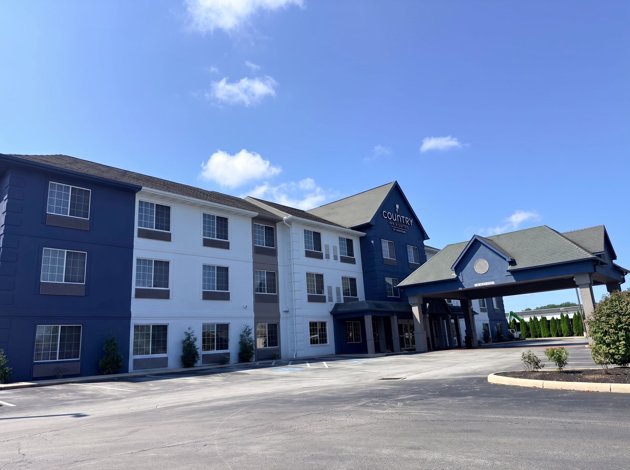 A multi-story hotel with a blue and white exterior, a covered entrance, and a parking lot.