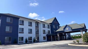 A multi-story hotel with a blue and white exterior, a covered entrance, and a parking lot.