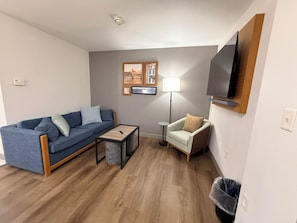 A living room with a sofa, armchair, coffee table, and a TV mounted on the wall. - Country Inn & Suites by Radisson, Lima (Lima)