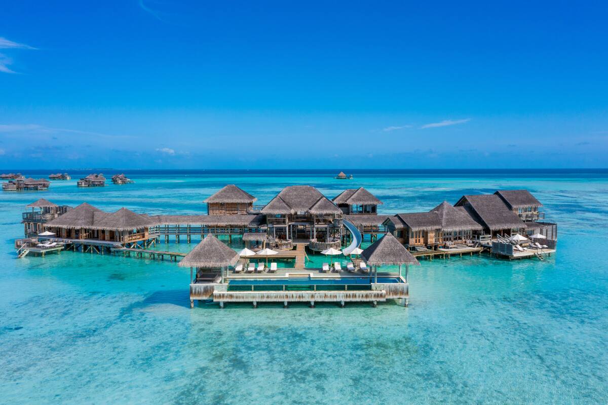 Wasserbungalows mit Strohdach, klares türkisblaues Wasser und eine Holzterrasse.