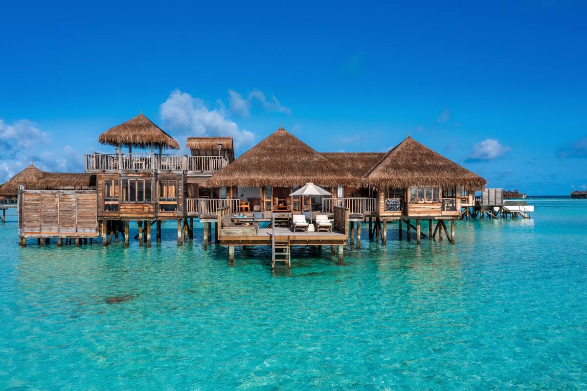 Wasserbungalows mit Strohdächern, hölzernen Stegen und klarem, türkisblauem Wasser.