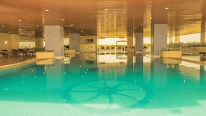 Een buitenzwembad, ligstoelen bij het zwembad