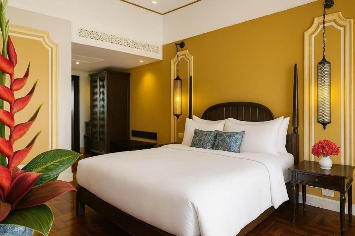 Ein Hotelzimmer mit einem großen Bett, einem Nachttisch, einer Zimmerpflanze und einer Wandleuchte.