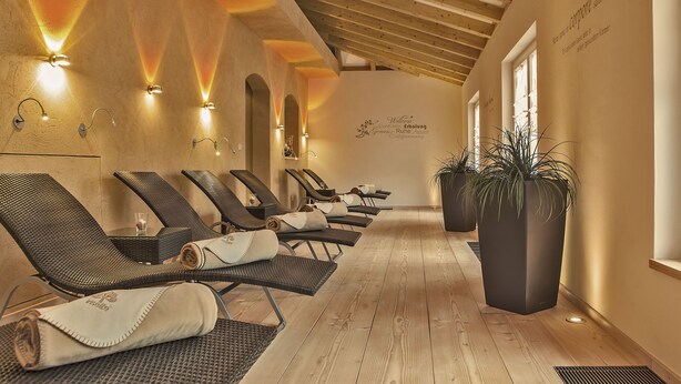 Un espace détente avec des fauteuils inclinables, un plancher en bois et des lampes fixées au mur.