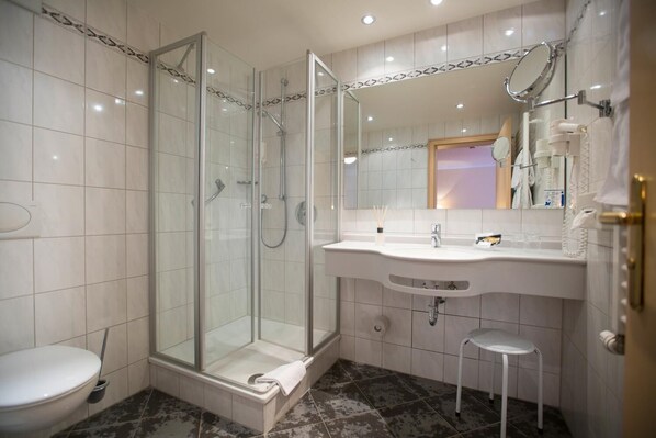 A modern bathroom with a glass-enclosed shower, a white sink with a mirror, and a toilet.
