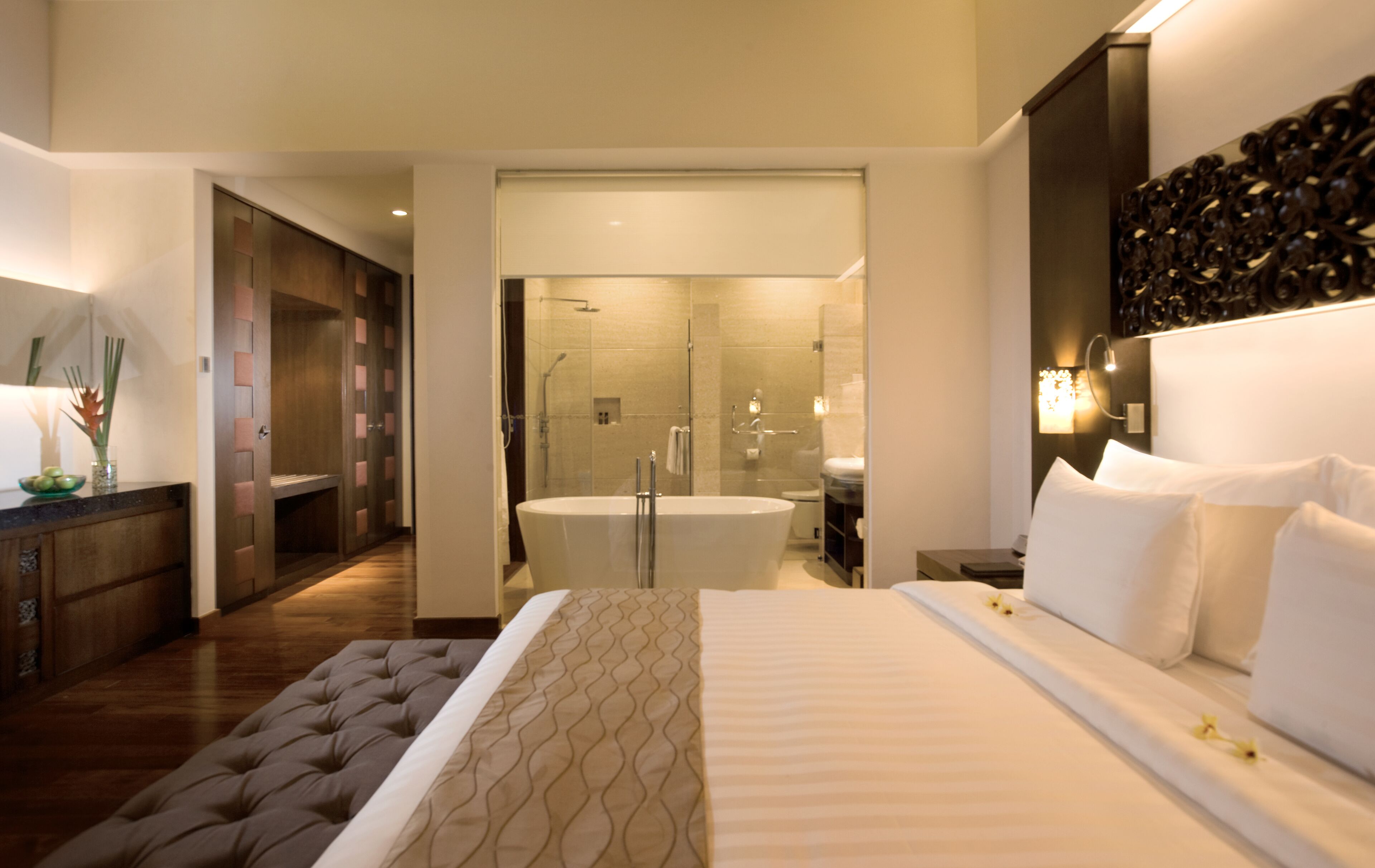 A modern hotel room with a large bed, a separate bathroom with a bathtub, and a walk-in closet.