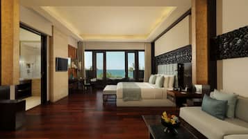 Habitación de hotel moderna con una cama grande, un sofá, un televisor y vista al océano.