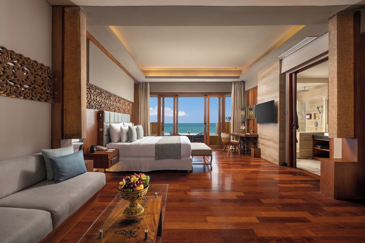 A spacious bedroom with a large bed, a sofa, and a dining area.