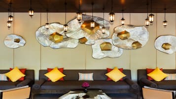 Uma sala de estar moderna com sofá, obras de arte decorativas e luminárias pendentes em estilo lanterna.