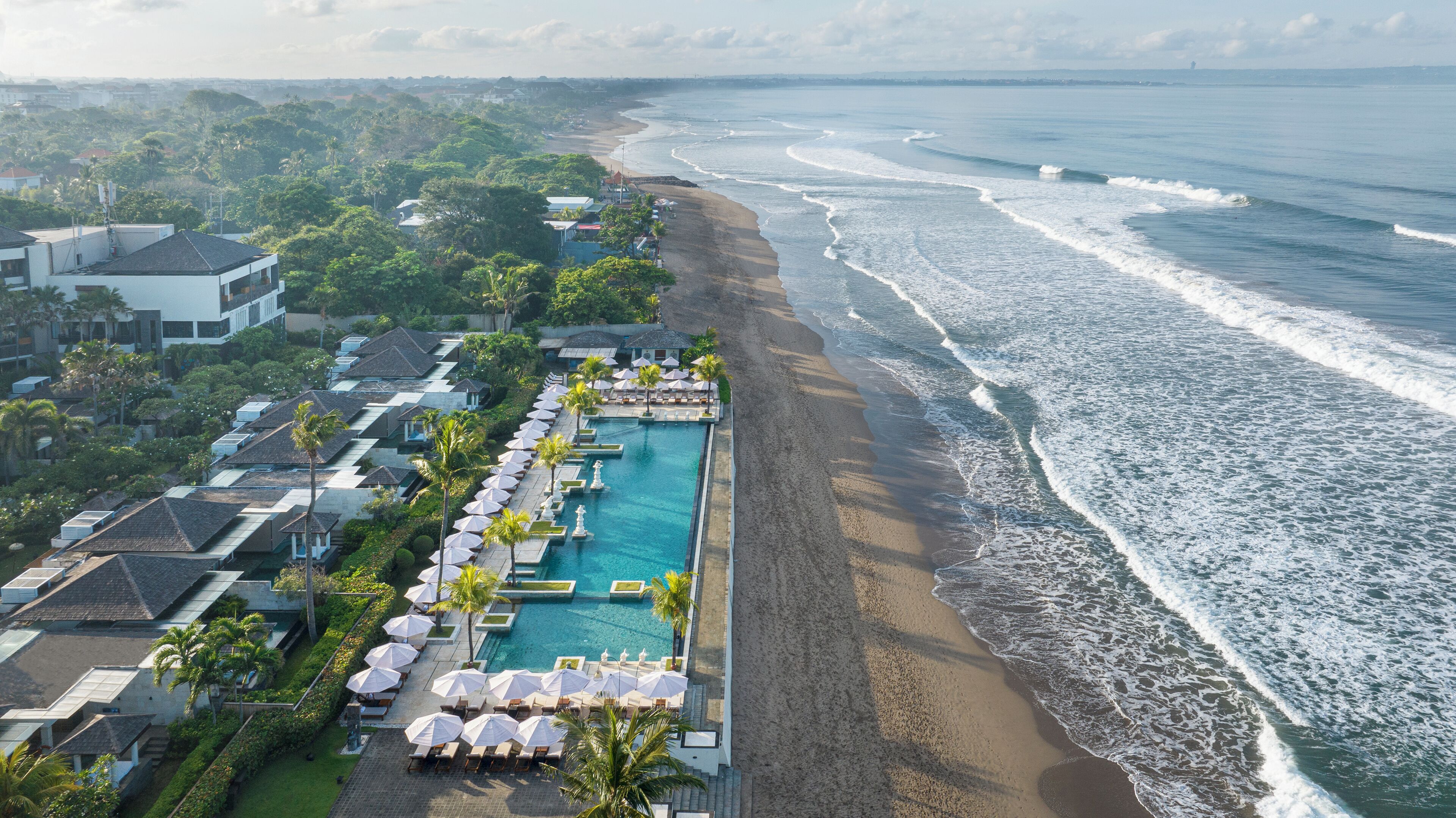 Resort com piscina extensa, acesso à praia e vista para o oceano.