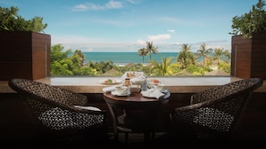 A table set for two with a view of the ocean and palm trees.