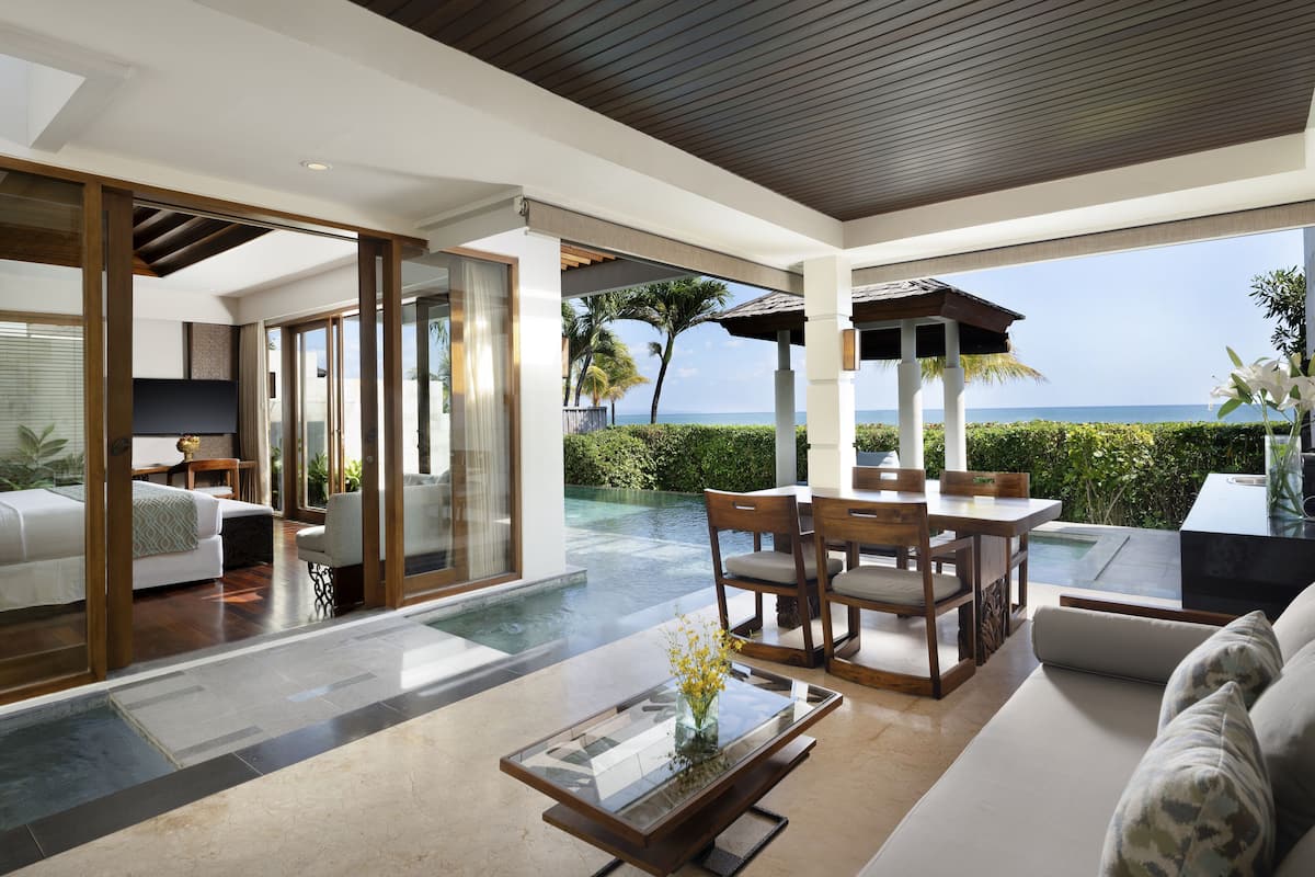 A modern hotel room with a large sliding glass door leading to a private pool area.