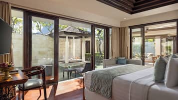 Um quarto espaçoso com uma cama grande, um espaço de estar com sofá e cadeiras, e vista para uma piscina e jardim através de grandes portas de vidro deslizantes.