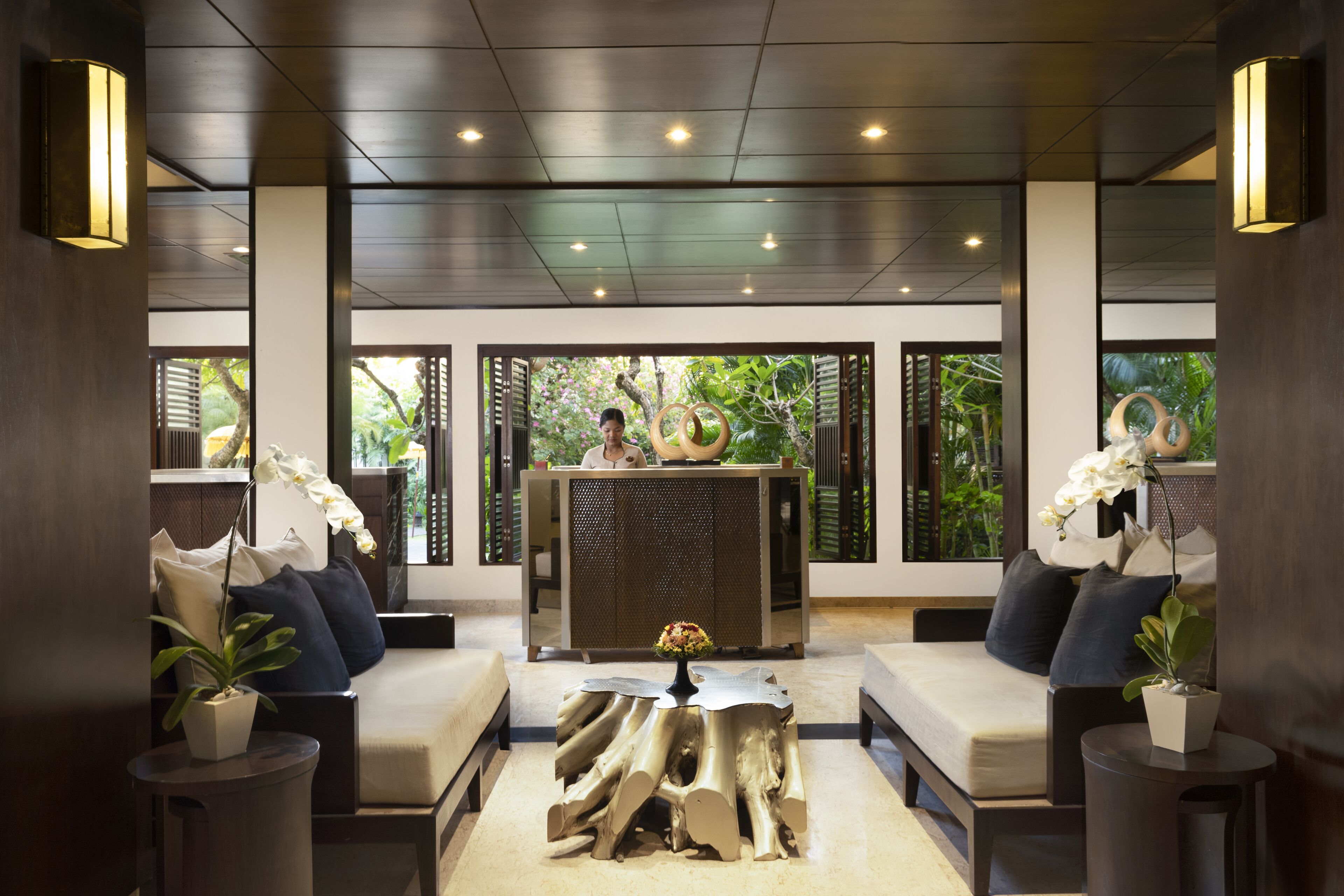 A modern lobby with a reception desk, seating area, and large windows with natural light.