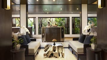 A modern lobby with a reception desk, seating area, and large windows with natural light.