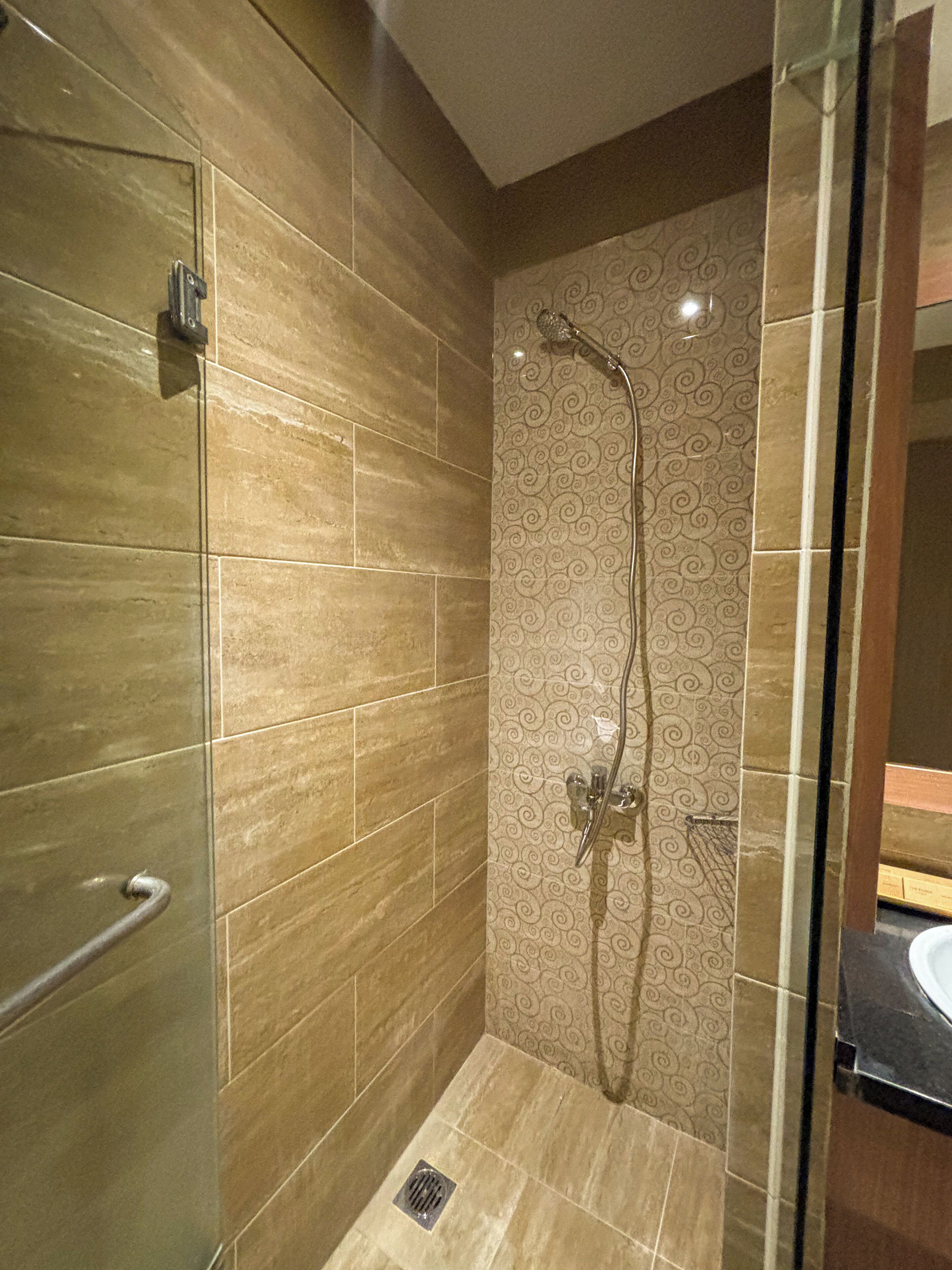 A modern bathroom with a glass shower enclosure, a patterned wall, and a sink area.