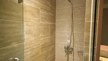 A modern bathroom with a glass shower enclosure, a patterned wall, and a sink area.
