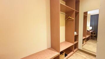 A walk-in closet with multiple shelves and hanging space, a bench, and a mirror.