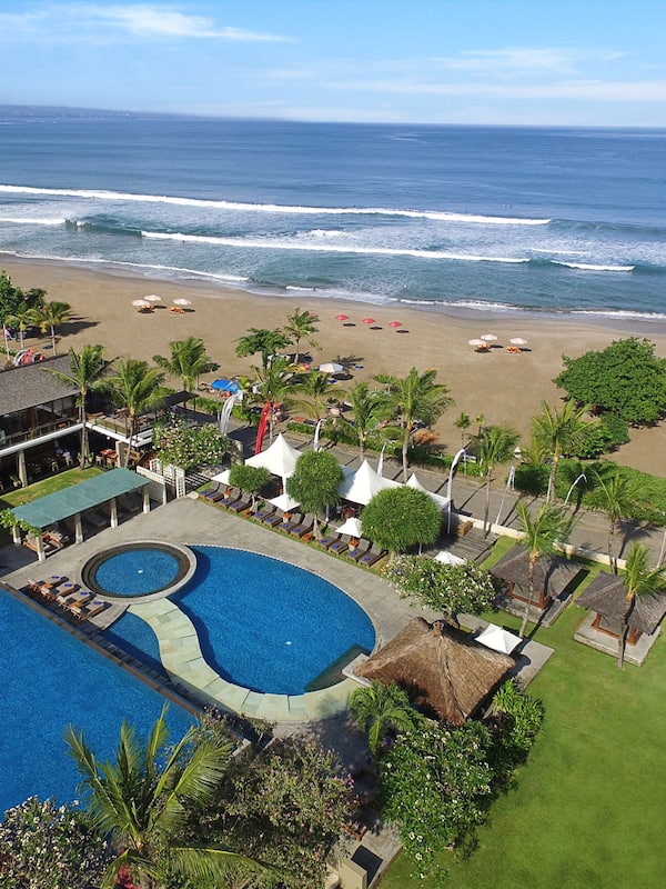 Relax by the pool or on the beach, surrounded by lush greenery and palm trees.