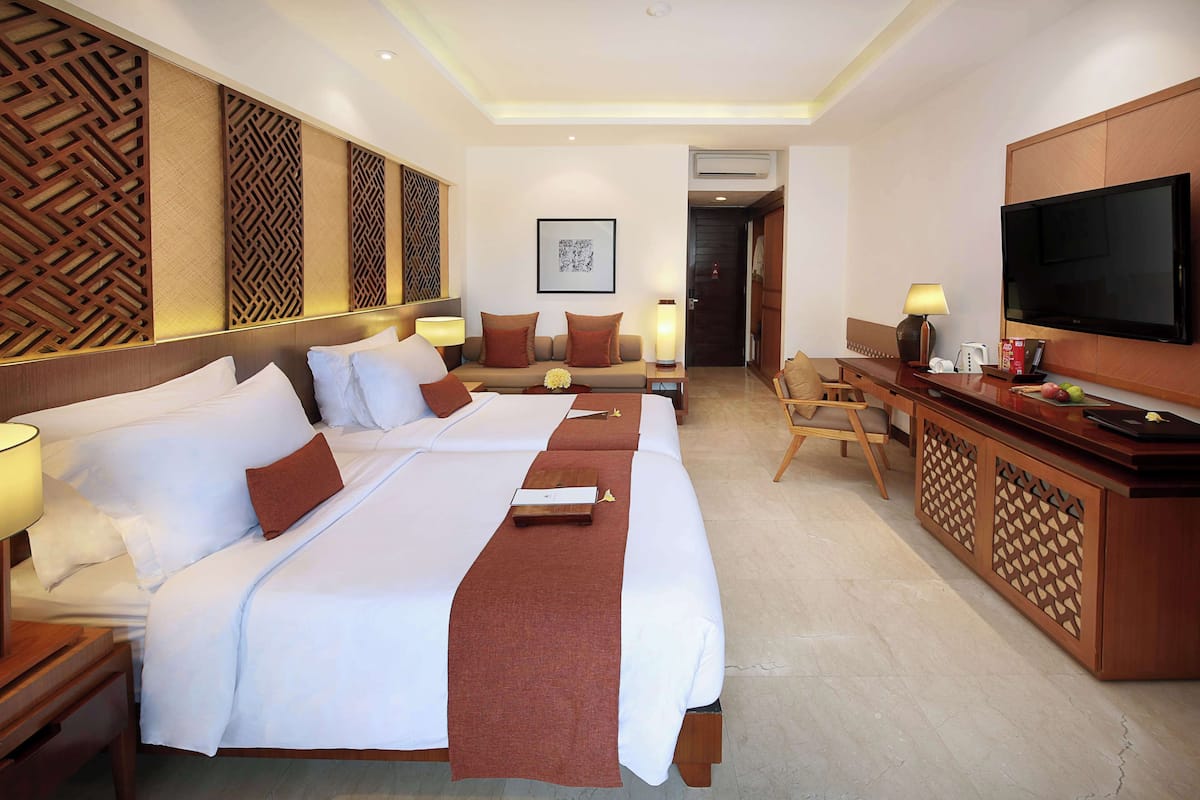 A hotel room with two beds, a TV, a desk, and a minibar.