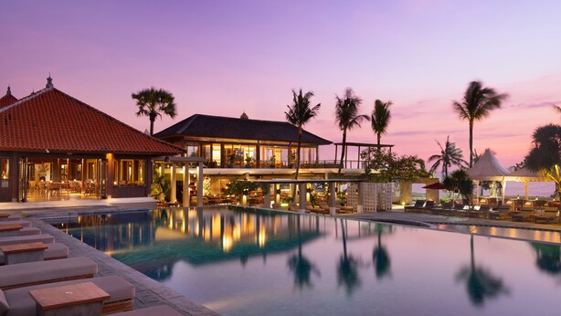 A resort with a swimming pool, lounge area, and a building with multiple levels and outdoor seating. - Bali Niksoma Boutique Beach Resort (Legian)