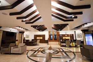 A hotel lobby with a reception desk, seating area, and a large star emblem on the floor. - Rivera Sarovar Portico Ahmedabad (Ahmedabad)