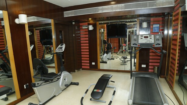 Un gimnasio con equipamiento de ejercicio, incluyendo cintas de correr, bicicletas estáticas y una máquina de remo.