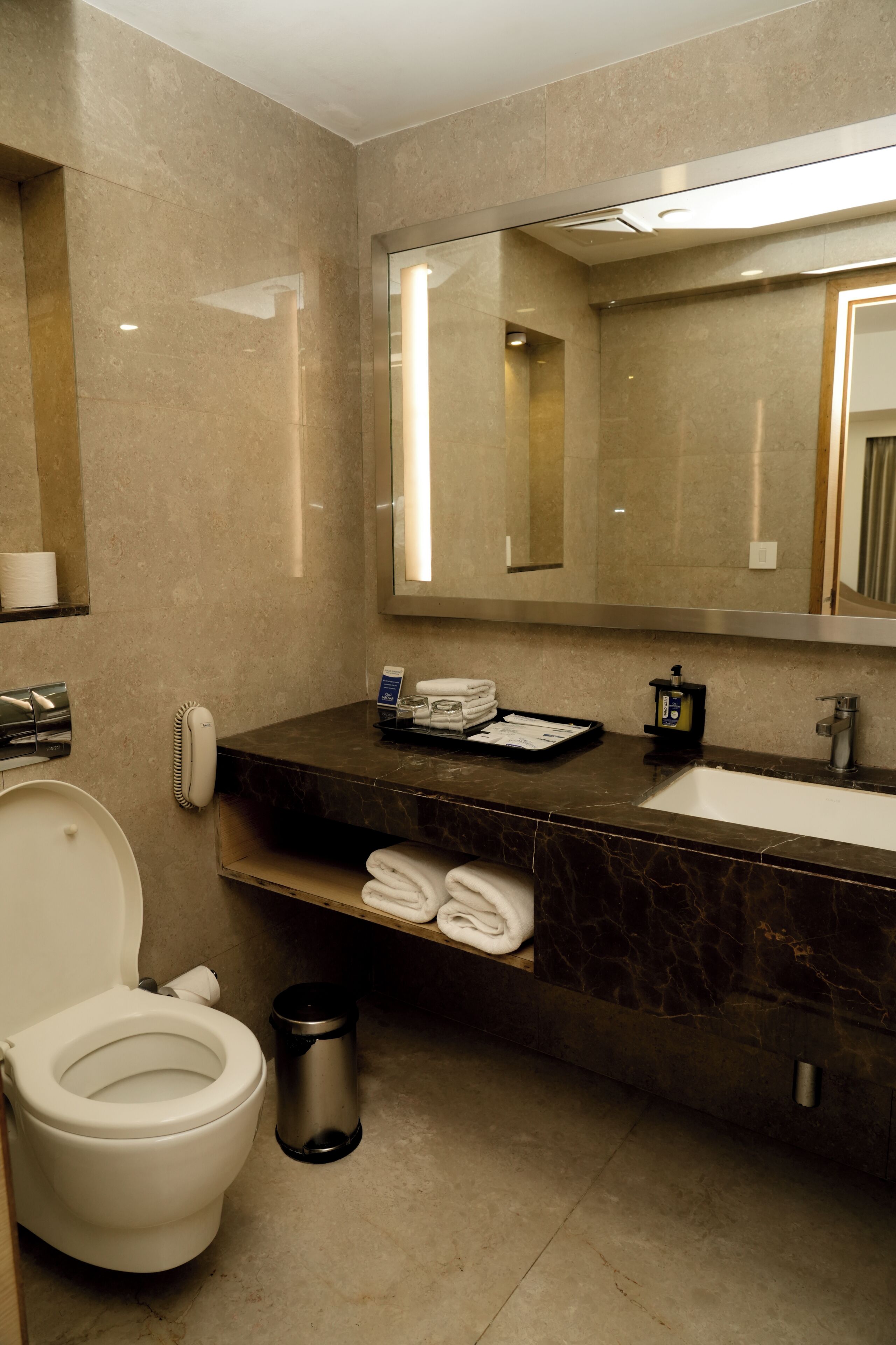 A modern bathroom with a toilet, sink, and mirror.