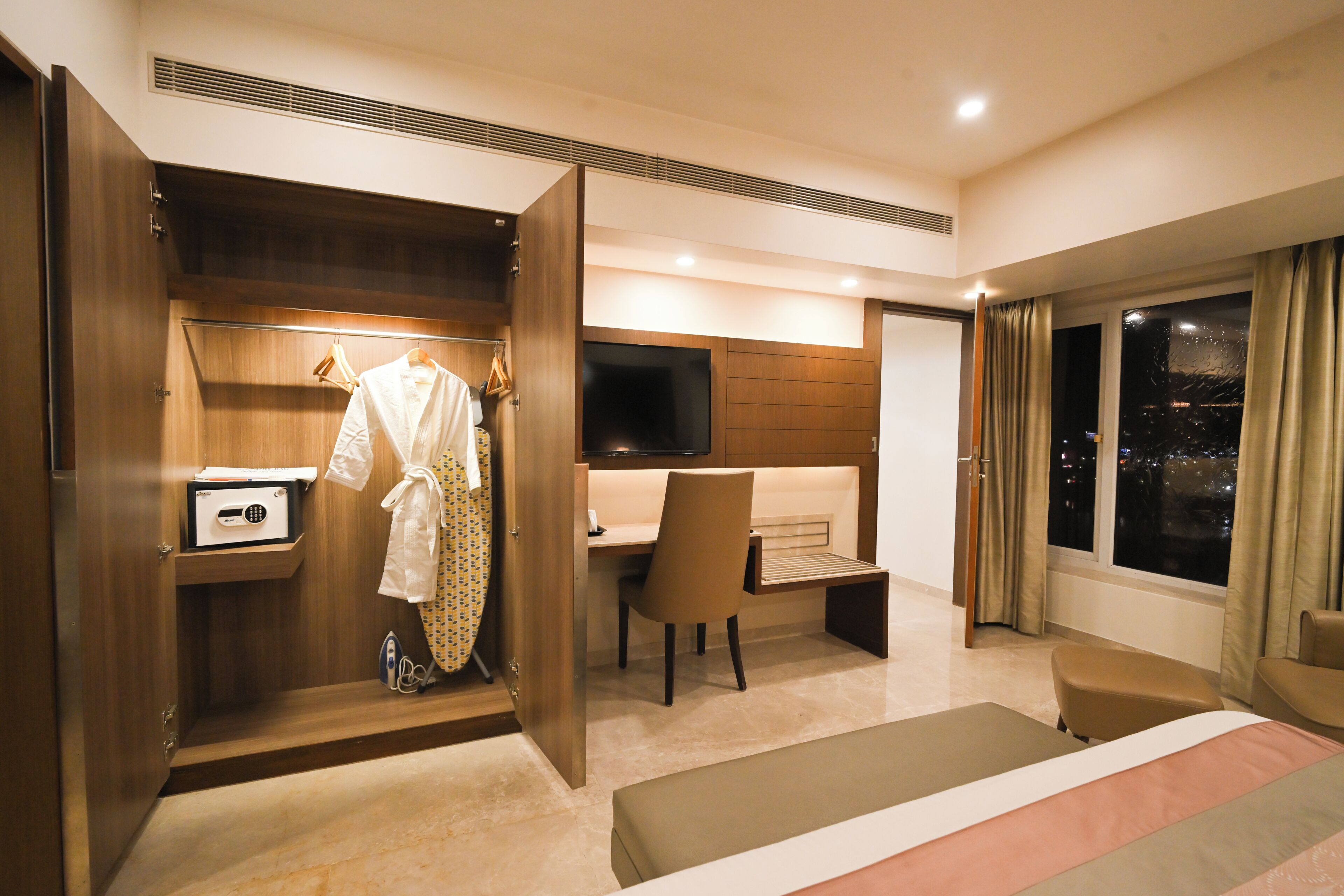 Habitación de hotel con vestidor, escritorio, silla, cama y televisor.