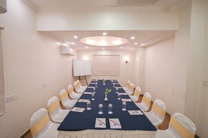 A conference room with a long table, white chairs, and a whiteboard.