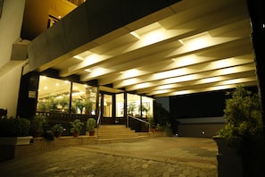 A building entrance with a covered walkway, potted plants, and a staircase leading to the entrance.