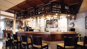 A bar area with a wooden counter, bar stools, and shelves with bottles. - AKZENT Hotel Koerner Hof (Dortmund)