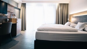 A modern hotel room with a large bed, a desk with a computer, and a TV. - AKZENT Hotel Koerner Hof (Dortmund)