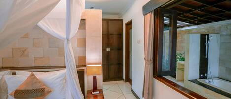 A bedroom with a bed, a nightstand, a lamp, and a window with curtains.