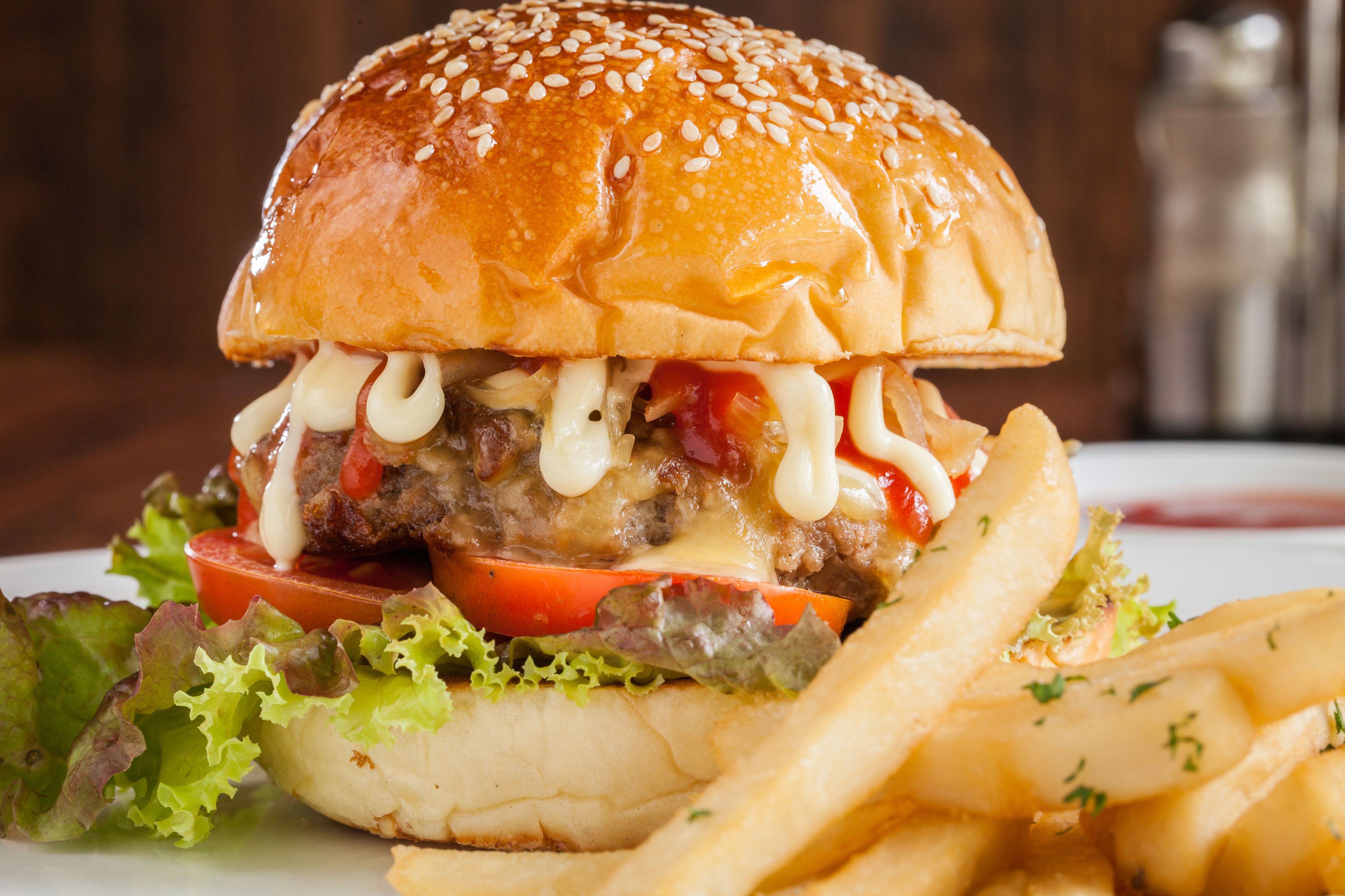Hamburguesa con lechuga, tomate y queso, acompañada de papas fritas.