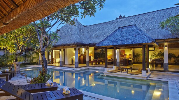 A resort with a swimming pool, outdoor seating, and a thatched-roof structure. - The Maya Seminyak Villas (Seminyak)