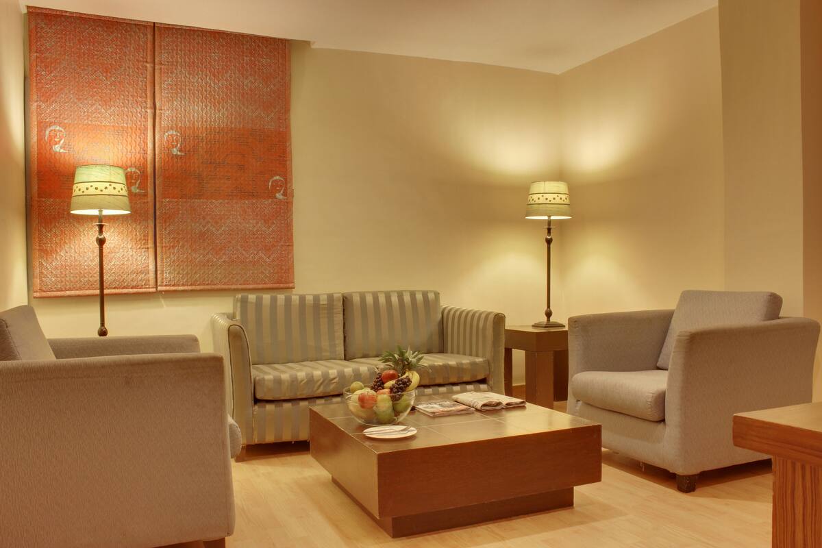 Un salon moderne comprenant un canapé, des fauteuils, une table basse et deux lampadaires.