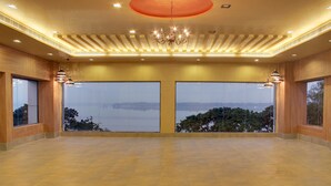 A spacious room with large windows offering a view of a body of water and trees. - juSTa Hyderabad (Hyderabad)