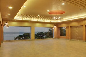 A spacious room with large windows offering a view of trees and a body of water.