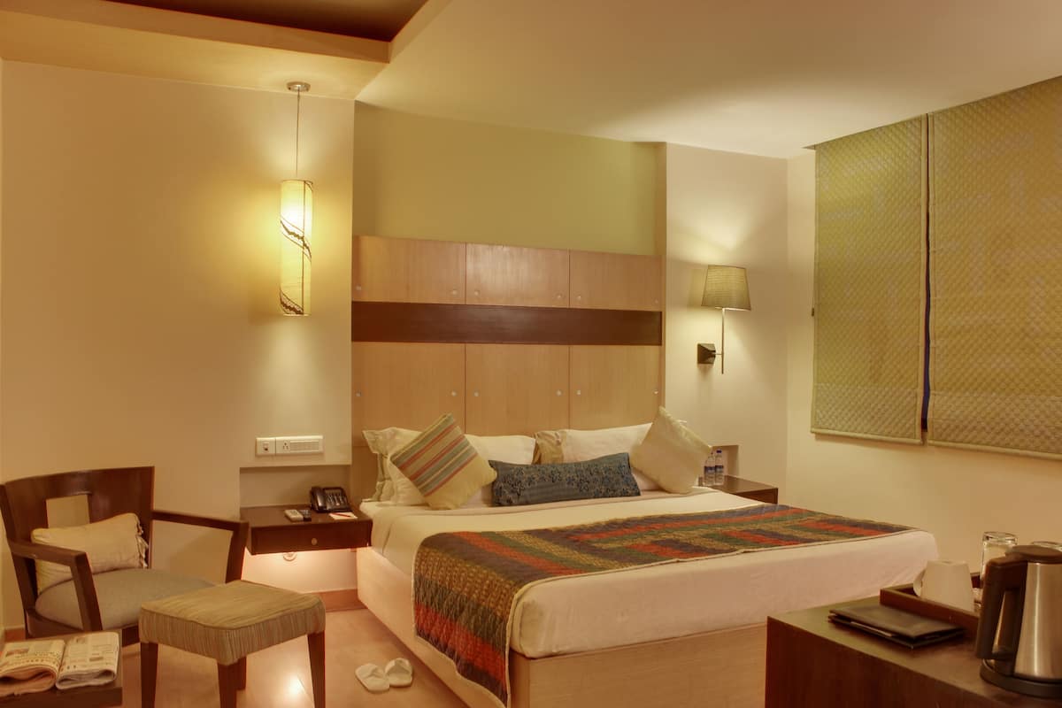 Une chambre d’hôtel comprenant un lit, des tables de chevet, une chaise, un bureau et une lampe.