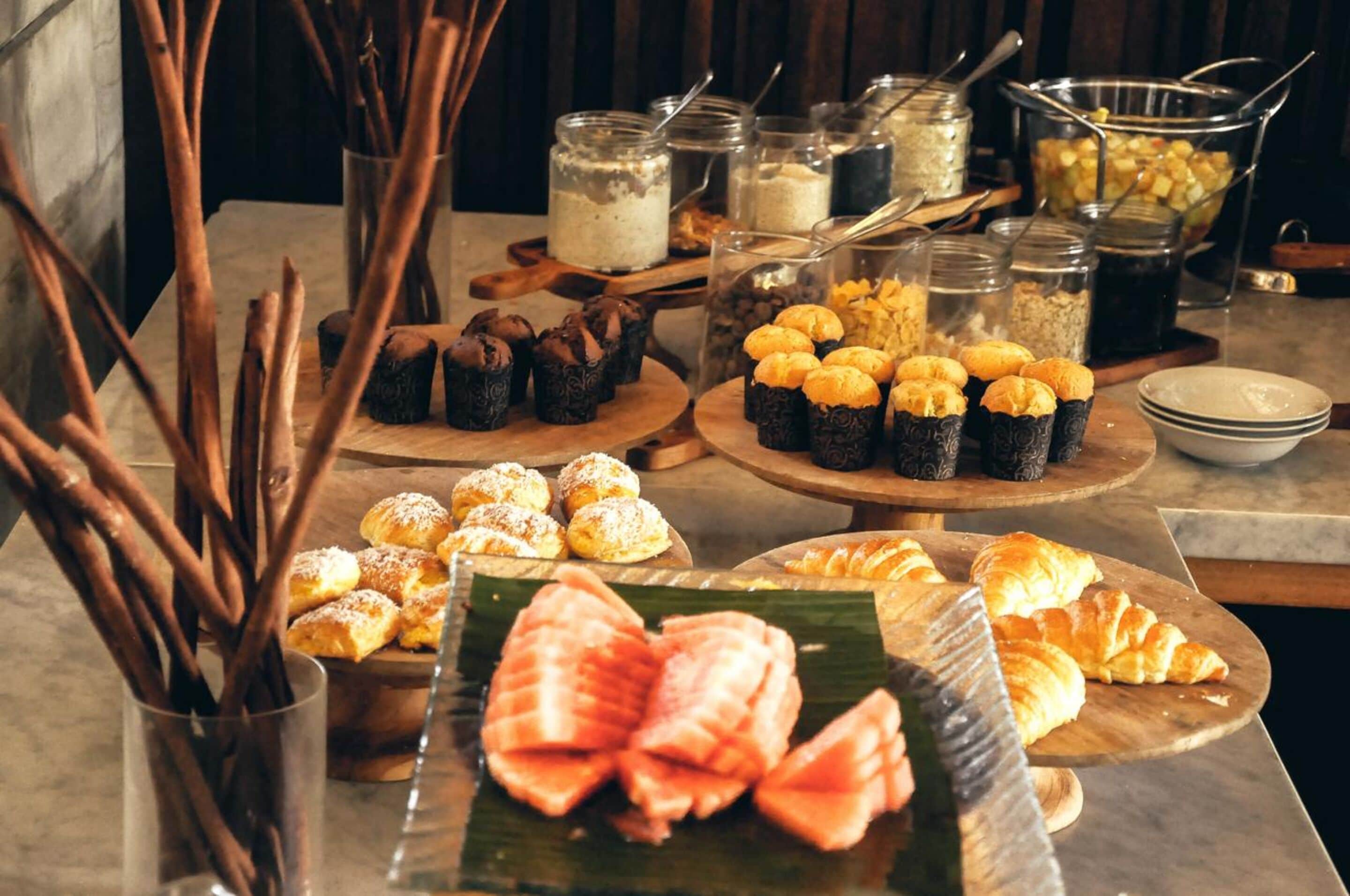 A buffet table with various pastries and desserts, including croissants and muffins, arranged on wooden boards.