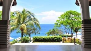 A covered outdoor area with a view of the ocean and palm trees. - Blue Point Resort and Spa (Pecatu)
