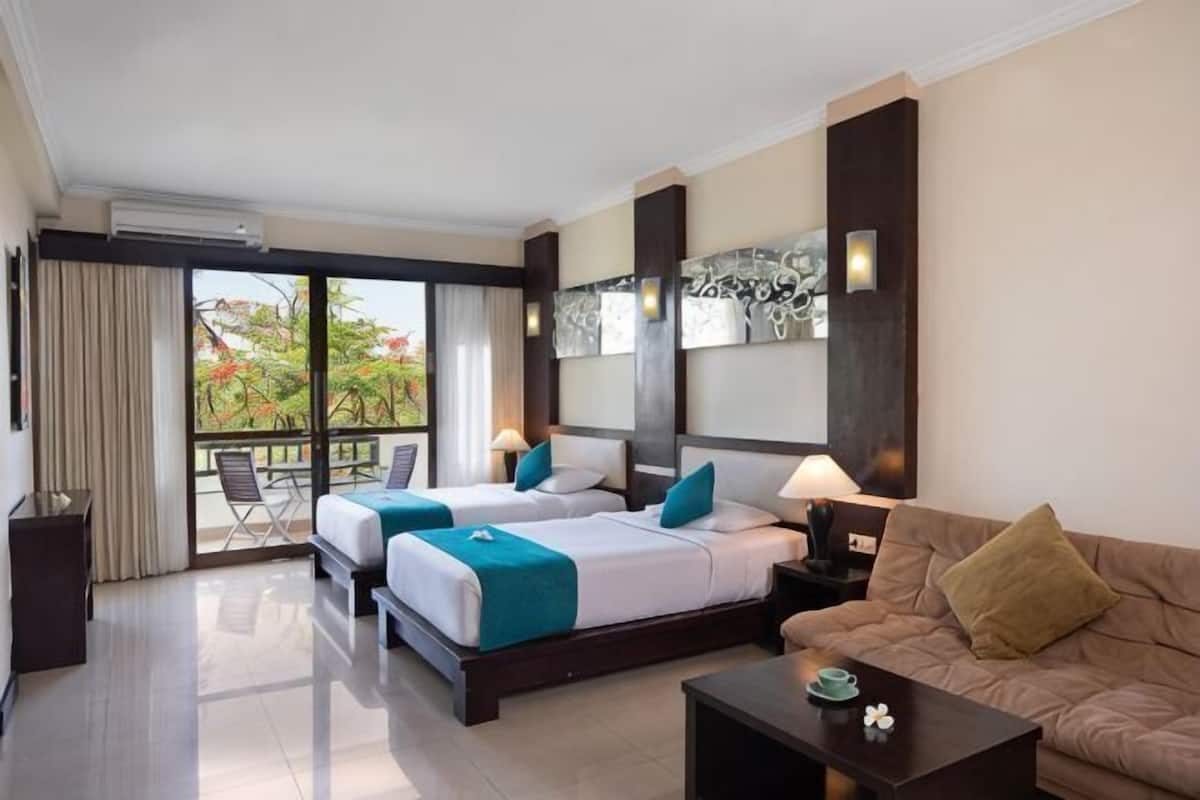 A hotel room with two beds, a sofa, a balcony with a view, and a dining area.