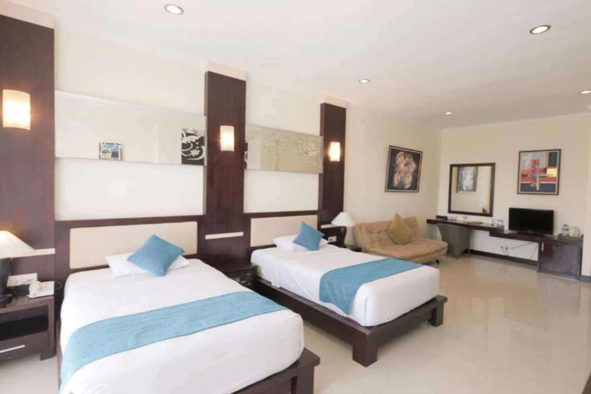 A hotel room with two beds, a desk, a chair, a TV, and a wardrobe.