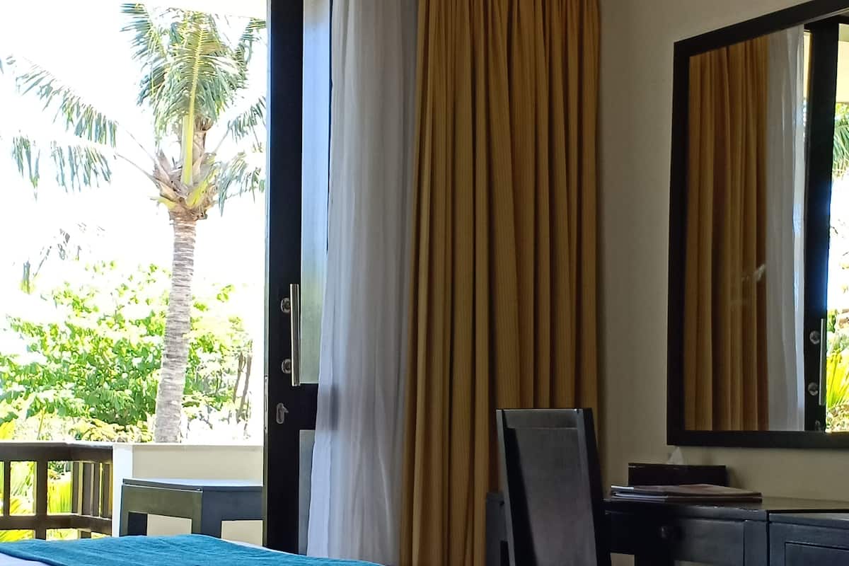 A hotel room with two beds, a desk, a chair, and a large window with curtains.