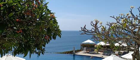 Zona de piscina con sillas de descanso y sombrillas, vista despejada al océano, y un cartel que dice "BLUE POINT BAY VILLAS & SPA".